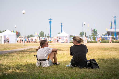 Bobruisk, Belarus July 17, 2021. Mom and daughter on the lawn in front of the site of a mass event, concert.