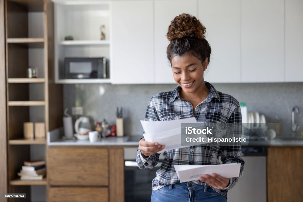 Happy woman at home checking her mail Portrait of a happy Latin American woman at home checking her mail and smiling - lifestyle Mail Stock Photo