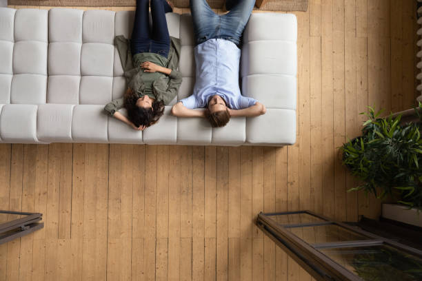 istock Couple put hands behind head relaxing on sofa, above view 1389740865