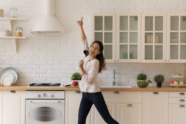 istock Woman distracted from cooking, holds ladle singing dancing in kitchen 1389741103