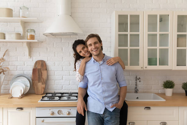 istock Wife cuddling husband looking at camera, resting in cozy kitchen 1389741104