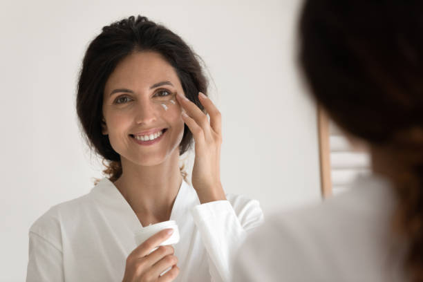 istock Woman holds jar apply cream on outer corners of eyes 1389741149