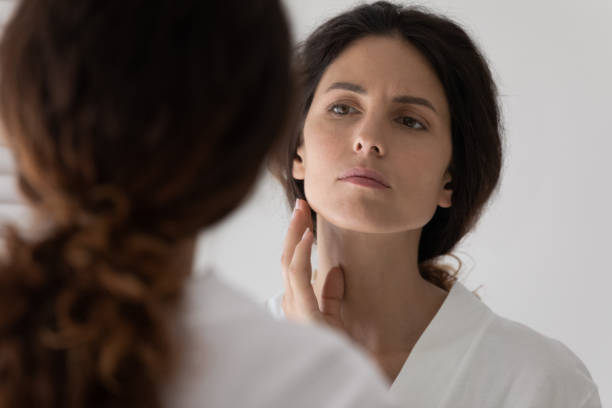istock 30s woman looks in mirror touch face feels upset 1389741994