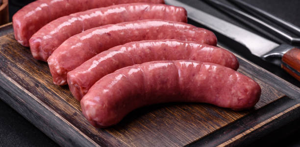 istock Raw sausages with ingredients on a cutting board on a stone background with copy space 1389742244
