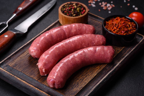 istock Raw sausages with ingredients on a cutting board on a stone background with copy space 1389742297