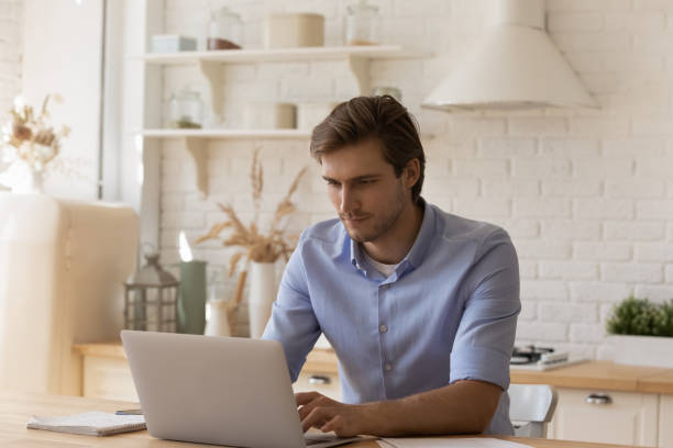istock Handsome thoughtful man sit at table working on laptop 1389742339