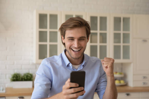 istock Man holds cellphone receive sms with great news feels overjoyed 1389742351