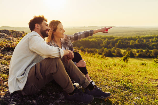 jeune couple assis ensemble regardant le paysage de campagne lors d’une randonnée estivale dans le jura, pologne - rural watch photos et images de collection