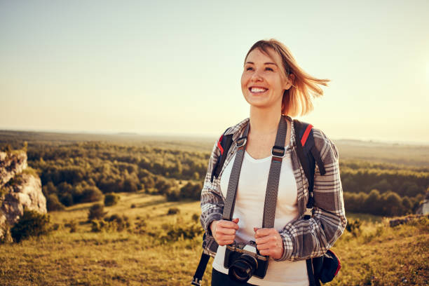 istock Young woman hiking in summer with backpack and camera 1389744321