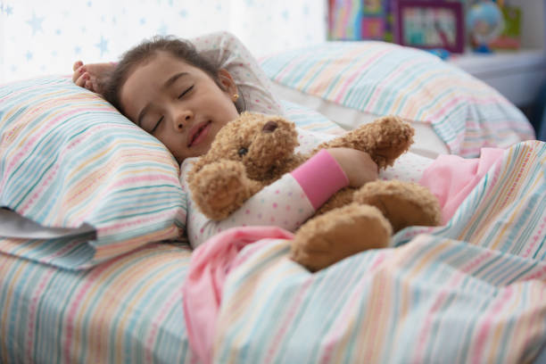istock little girl in bed sleeping with her teddy bear 1389745292