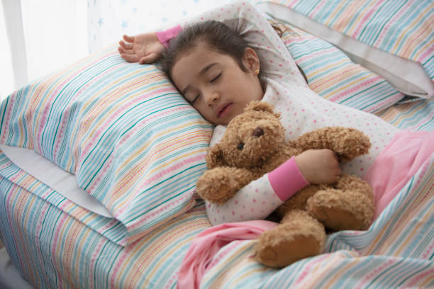 istock little girl in bed sleeping with her teddy bear 1389745294