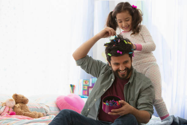 Little girl doing father's hair stock photo