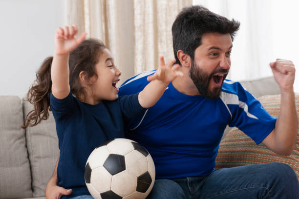 istock father watching sport game with daughter 1389745758