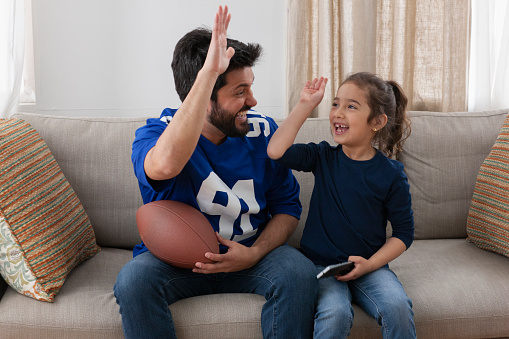 father watching sport game with daughter