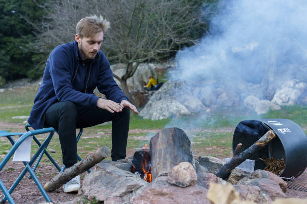 istock Man sitting by the fire and warming his hands at the blue hour. Camping concept 1389745829