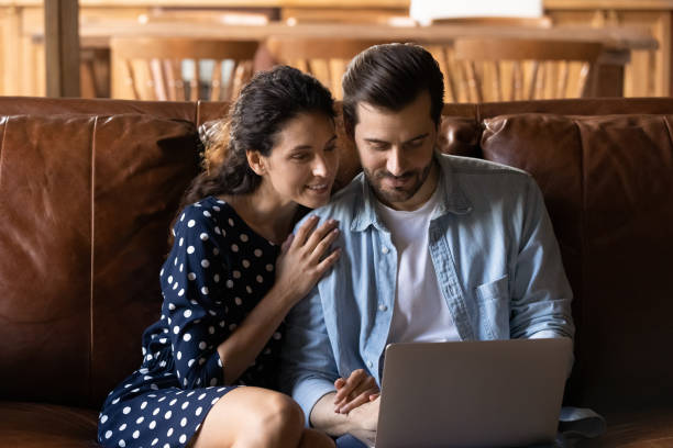 istock Loving young couple sit on couch look on pc screen 1389746497