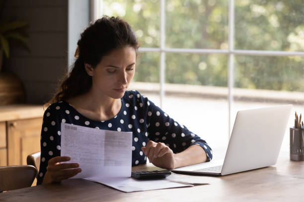 istock Focused young latin female doing financial paperwork at home kitchen 1389746504