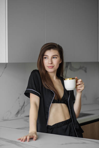 istock Young beautiful woman drinks morning coffee from white cup in kitchen. Rest and weekends. 1389746641