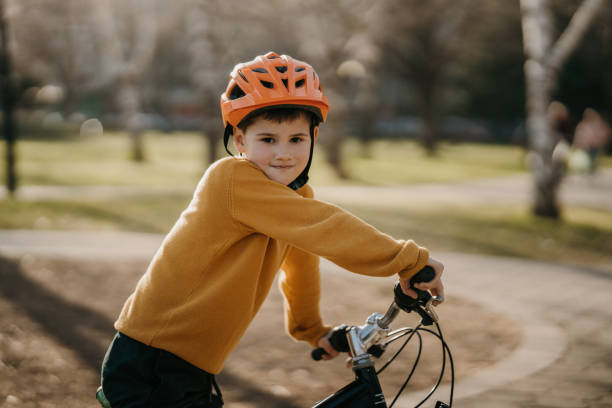 Young boy with cycling helmet riding a bicycle in public park
