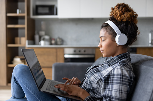 Mujer en casa trabajando en su computadora portátil y usando auriculares photo