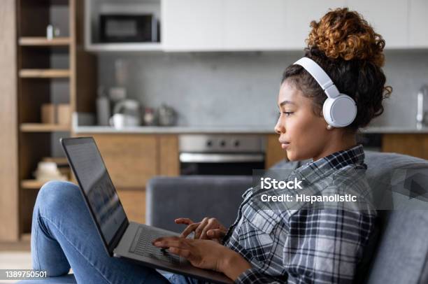 Woman At Home Working On Her Laptop And Using Headphones Stock Photo - Download Image Now