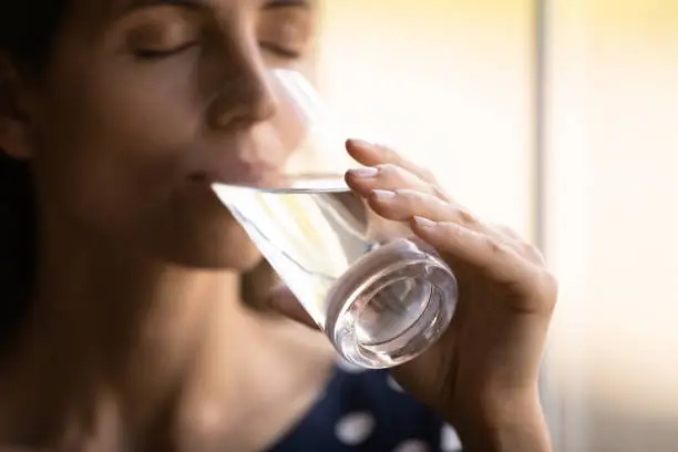 Photo of Thirsty millennial hispanic woman drinking cool water with closed eyes