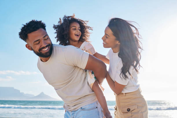 ビーチを散歩する3人の愛情深い若い家族のクロップドショット - アフリカ系 アメリカ人 ストックフォトと画像