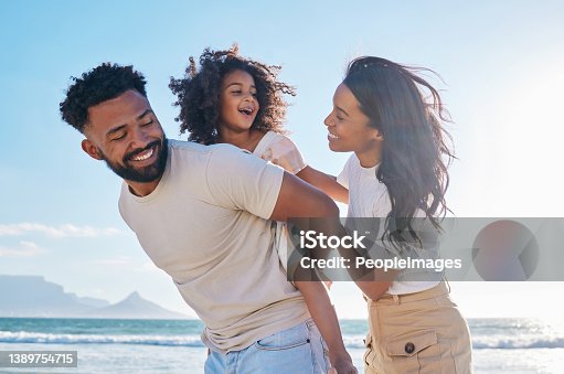 istock Cropped shot of an affectionate young family of three taking a walk on the beach 1389754715