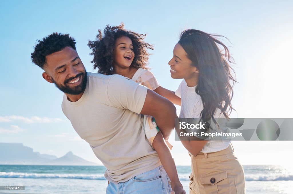 Cropped shot of an affectionate young family of three taking a walk on the beach Fun with the family Family Stock Photo