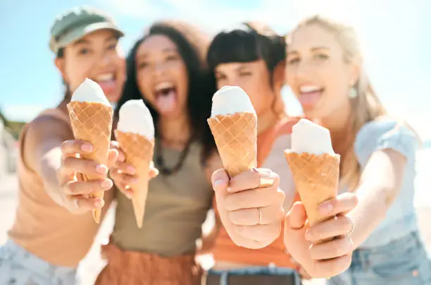 Photo of Cropped portrait of a group of attractive young girlfriends enjoying ice creams on the beach