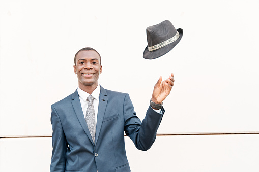 African-American businessman throwing a hat on a white stone backdrop