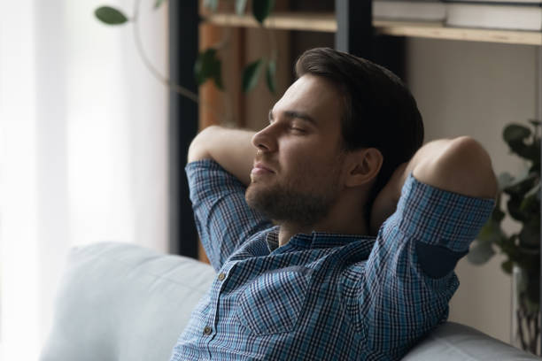 istock Man relaxing on sofa daydreams enjoy weekend at modern home 1389758514