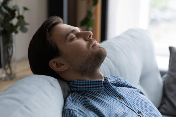 istock Close up handsome young man falling asleep on sofa 1389758528