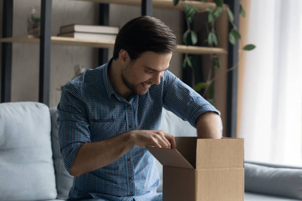 istock Man opening delivered parcel feels satisfied by online purchase 1389758557