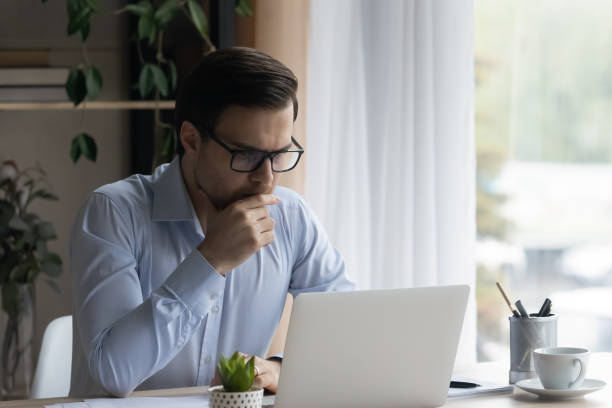istock Serious focused businessman looking at laptop learning new software 1389759713