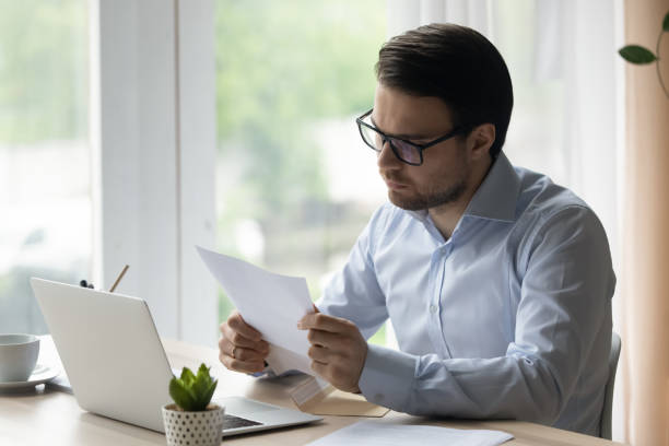 istock Serious businessman reading letter, sorting out correspondence in office 1389759785