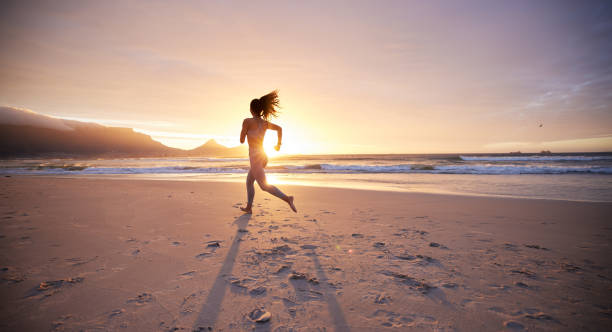 scatto di una giovane donna che pratica yoga sulla spiaggia - real estate immagine foto e immagini stock