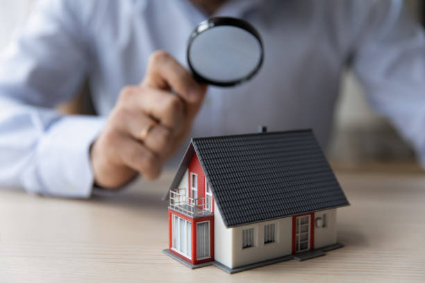 man appraiser hold magnifying glass examining cottage house miniature - real estate imagens e fotografias de stock