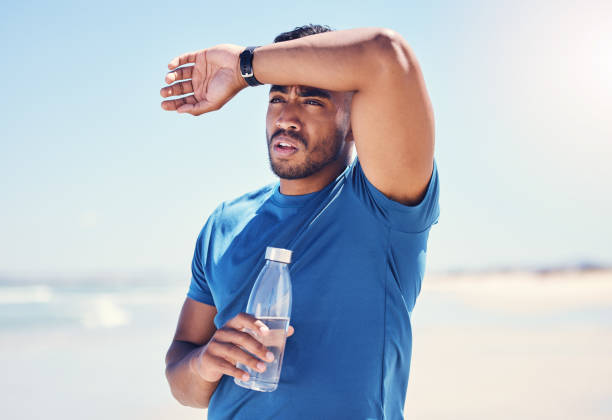 istock Shot of a man holding a bottle water while looking exhausted during his run 1389761015
