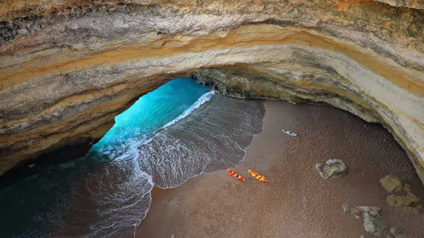 Sea kayaks resting on the small sand beach inside The Algar de Benagil Sea Cave-huge bell shaped room with two inlets from the sea and a big round hole in the middle of the ceiling. Algarve-Portugal.