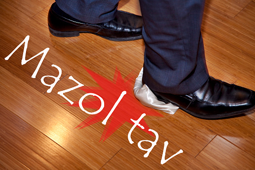 Breaking glass underfoot as part of Jewish wedding ceremony. With Mazol Tav text and splat symbol.