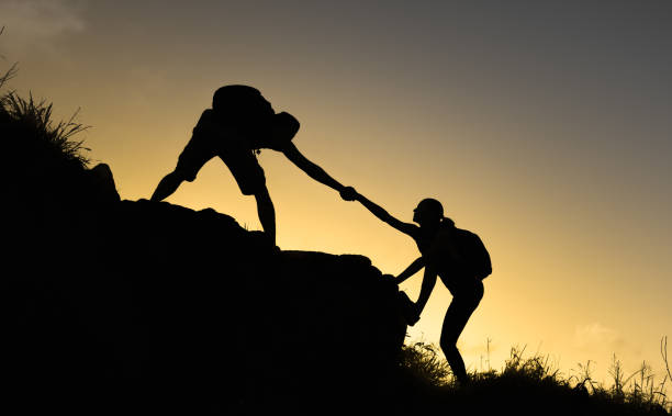 istock Men helping his friend hiker climb up the hill. 1389763393