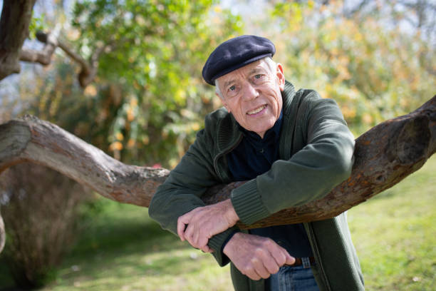 istock Close-up of aged man posing for camera under tree 1389763444