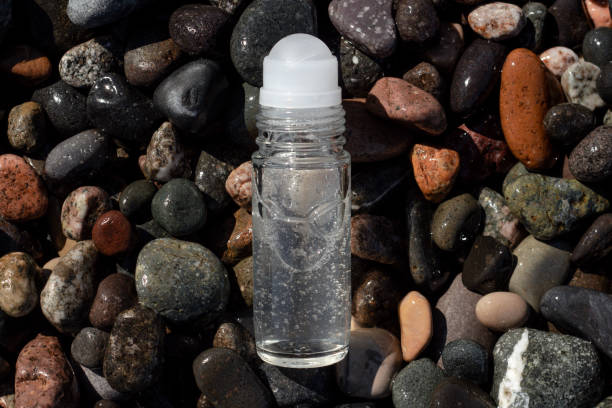 Flat lay composition of a roll on transparent deodorant bottle on wet beach stones