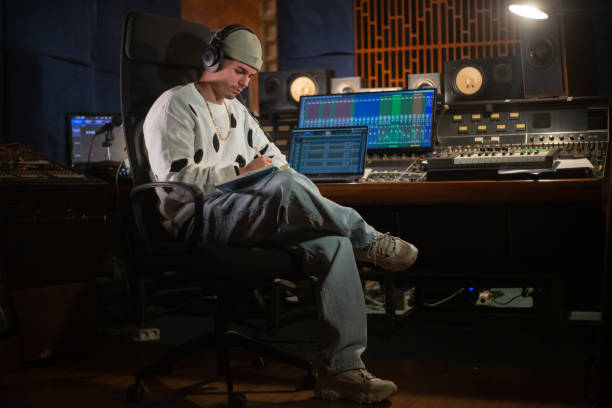istock Confident young music producer sitting at mixing console panel 1389763703