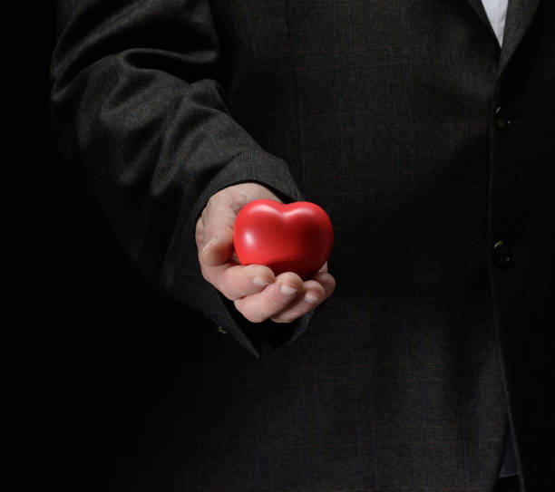 istock man's hand holds a red heart on a dark background 1389764341