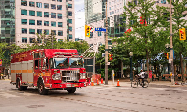 тяжелый спасательный грузовик red toronto fire services squad поворачивает с улицы кинга на улицу джона перед 27-этажным зданием metro hall в центре торонто - pumper стоковые фото и изображения