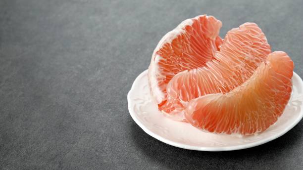 owoce pomelo na talerzu. grejpfrut, jeruk bali lub bali pomelo fruit. duże pomarańcze w indonezji są znane jako bali oranges lub jeruk bali. - pilled zdjęcia i obrazy z banku zdjęć