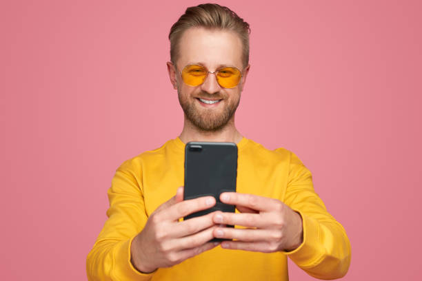 istock Cheerful man in sunglasses using smartphone 1389780205