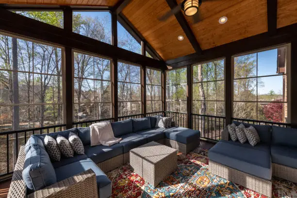 Contemporary screened porch in springtime, full of blooms trees in the background.